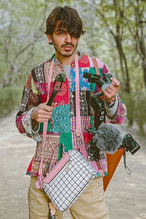 Farhan Khan holding all photography set and his girlfriend's purse. With his hair's falling perfectly on his one eye