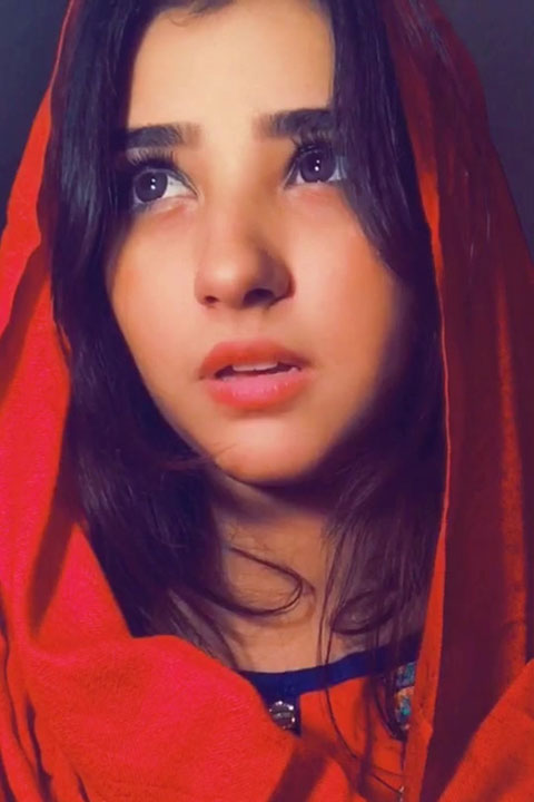 Hazeera wearing red dupatta (veil). She is looking intensely at side.
