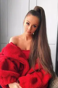 Holly H wearing red top. She has long bun and perfect tan.