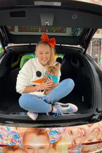 Jojo Siwa with cute dog in her hands and orange bow on her head