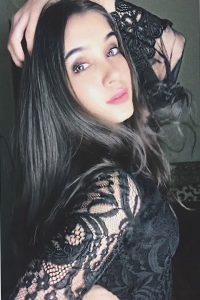 Reeja jeelani posing with her hand on her back and wearing black dress