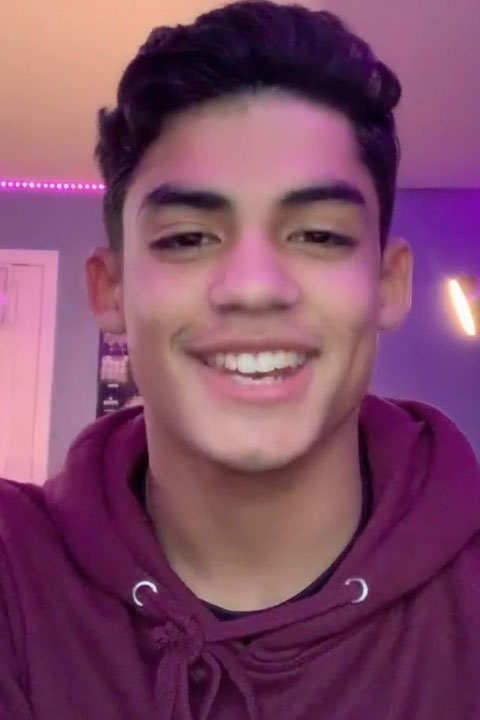 Alejandro Rosario in purple hoodie smiling at the viewer