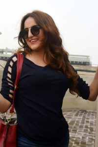 Hareem Shah in blue top exposing her arms and wearing black glasses
