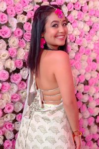 Neha Kakkar wearing white backless dress and looking at camera with perfect smile