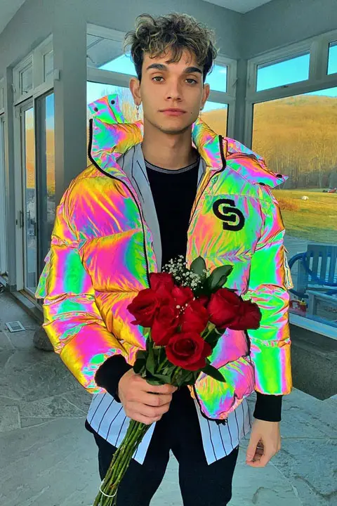 Marcus Dobre wearing colourful hoodie and holding roses.