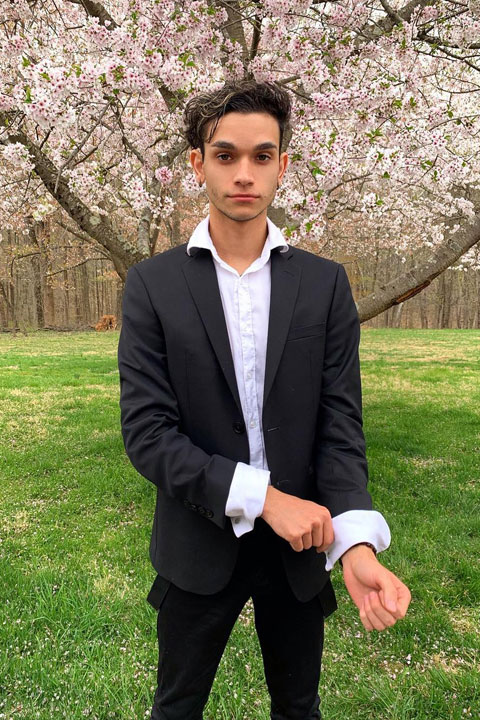 Marcus Dobre standing under cherry blossom tree wearing a suit.