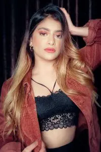 Famous Indian tiktok star Anam Darbar wearing black top and red overshirt. She is owning her body and showing it with confidence while wearing pinkish red lipstick