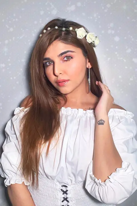 Ashi Khanna looking beautiful and glamorous in white dress and looking mysteriously at camera with her green eyes. She has crown tattoo on her wrist.