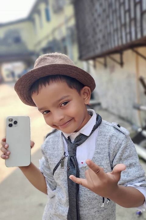 Sadim Khan holding iphone 11 and smiling at camera while making signs with his hand