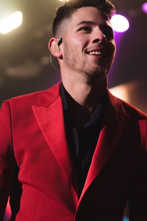 Nick Jonas is smiling and looking beautiful in red coat