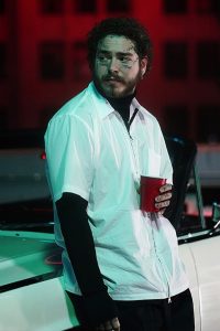 Post Malone holding red cup in white shirt and black pent