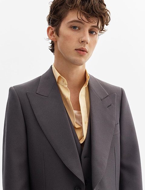 Troye Sivan in cream color shirt and grey coat