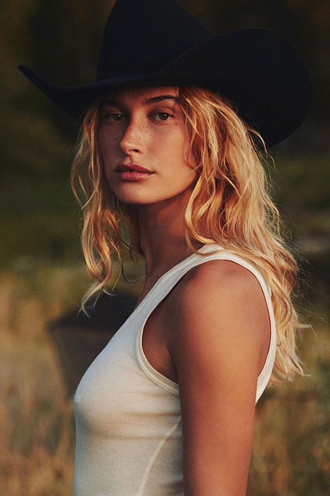 Hailey Bieber is looking hot in white sleeveless shirt and black hat.