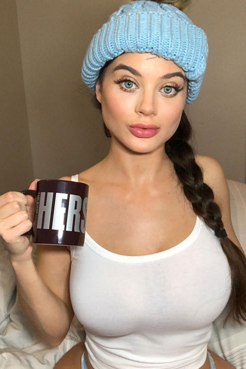 Lana Rhoades wear a blue cap and she is drinking her tea/coffee in dark brown cup.