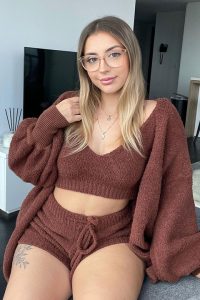 Lilith Cavaliere is looking stunning in brown blouse and shorts and she is wearing glasses and a beautiful pendant.