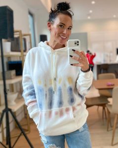 Heidi D'Amelio taking selfie in white hoodie and blue jeans
