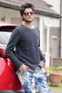 Nadeem Mubarik posing infront of red car