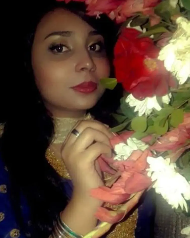 Neha Hussain posing in front of beautiful flowers