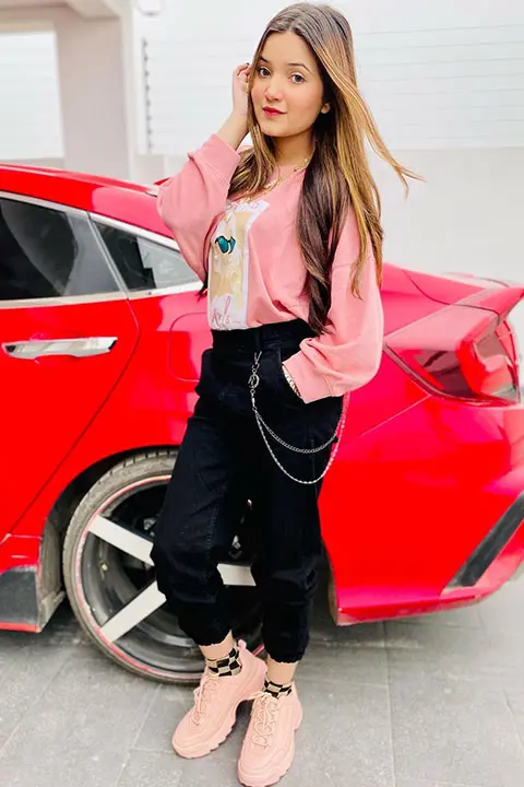 Rebecca khan standing infront of red civic car in pink shirt and black pents