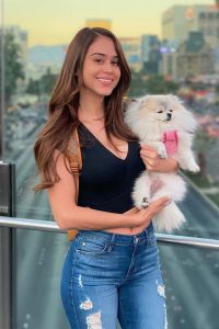 Yanet Garcia is posing for a picture with her dog.