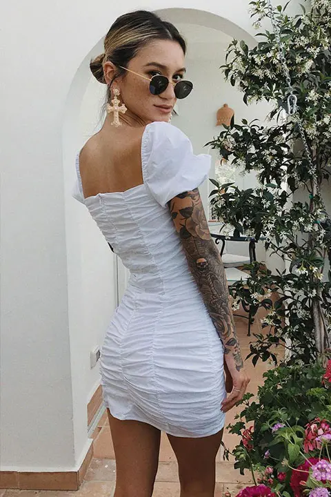 Jenah Yamamoto in white outfit looking behind and wearing sun glasses