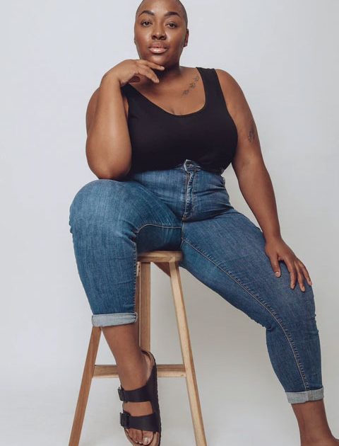 Nyome Nicholas-Williams sitting on stool in black top and blue jeans
