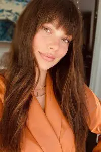 Camila Morrone taking selfie in orange coat