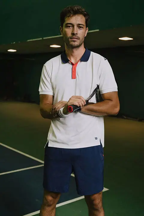 Francisco Lachowski posing with his racket in white polo and blue short