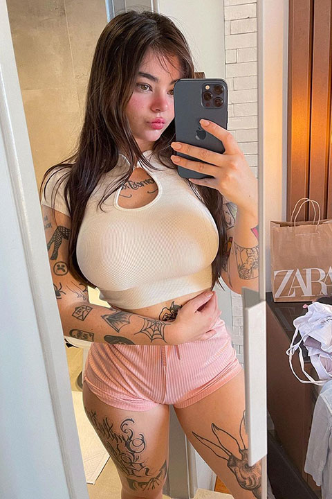Jessica Beppler taking her selfie in white shirt and pink shorts