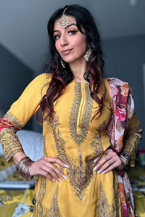 Aaliyah Yasin in a yellow embroidered dress, hands on hips